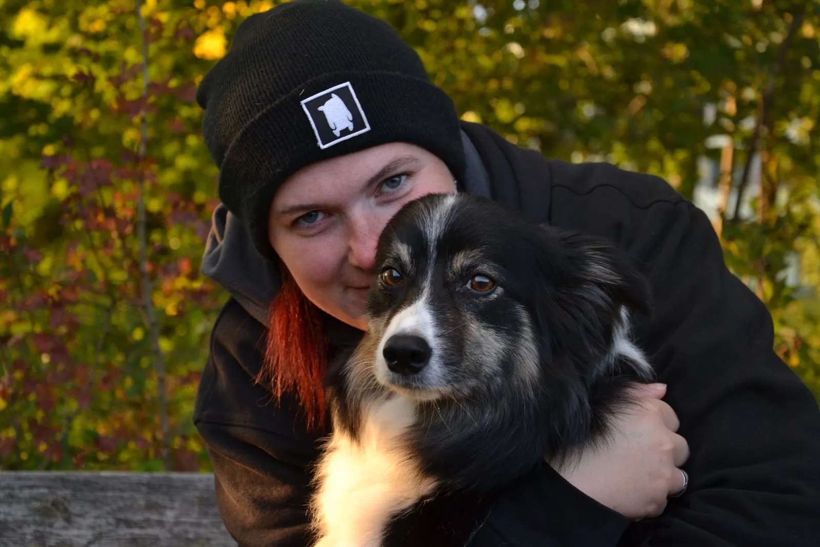 Denise Sättler umarmt ihren Border Collie im Herbstlaub